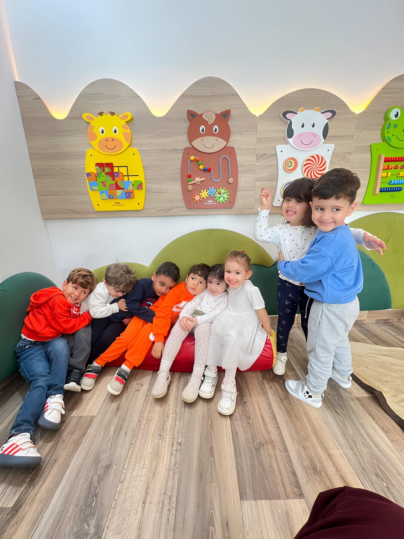 Des enfants dans le coin lecture, devant un mur décoré d’animaux